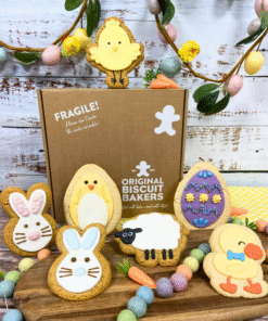 Easter biscuit gift box with hand‑iced gingerbread and sugar cookie characters including bunnies, chick, sheep and decorated Easter eggs, displayed in front of branded packaging.