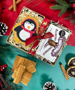 Christmas gift box featuring Billington's Gingerbread fingers and an Original Biscuit Bakers hand-iced gingerbread penguin biscuit, presented with festive ribbon and seasonal decorations.