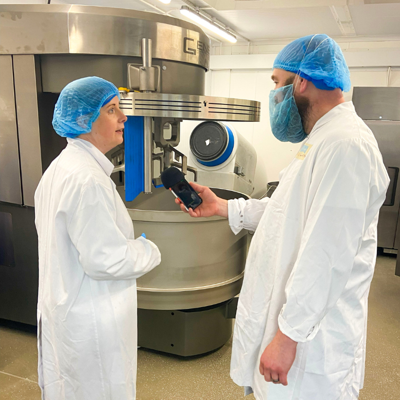 Managing Director Gemma Williams of Original Biscuit Bakers speaking to Adam Green from BBC Radio Shropshire. Large Mixer machine in background.