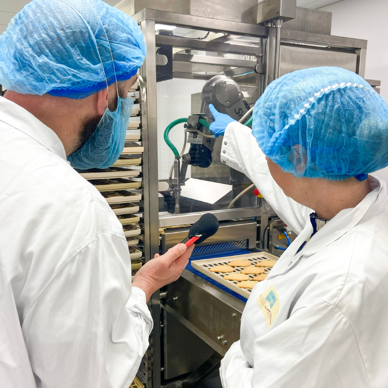 Adam Green from BBC Radio Shropshire with Managing Director Gemma Williams viewing the robotic biscuit decorating process at Original Biscuit Bakers.