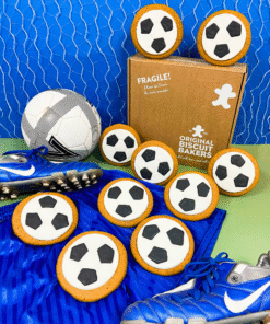 Football‑shaped iced gingerbread biscuits arranged with blue football boots, a football, and Original Biscuit Bakers branded box on a green and blue background.