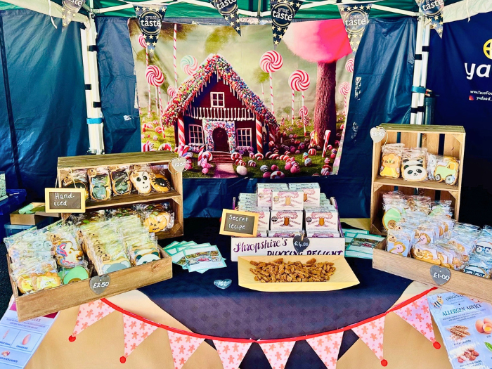 Image on Food Ltds's Food stand at the Ginger and Spice Festival 2026, displaying colourful hand-iced biscuits, packaged treats and samples, with a gingerbread house backdrop.
